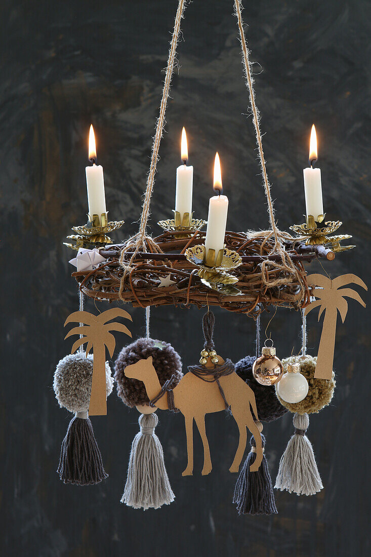 Hanging DIY Advent wreath with four lit candles and a camel with palm trees