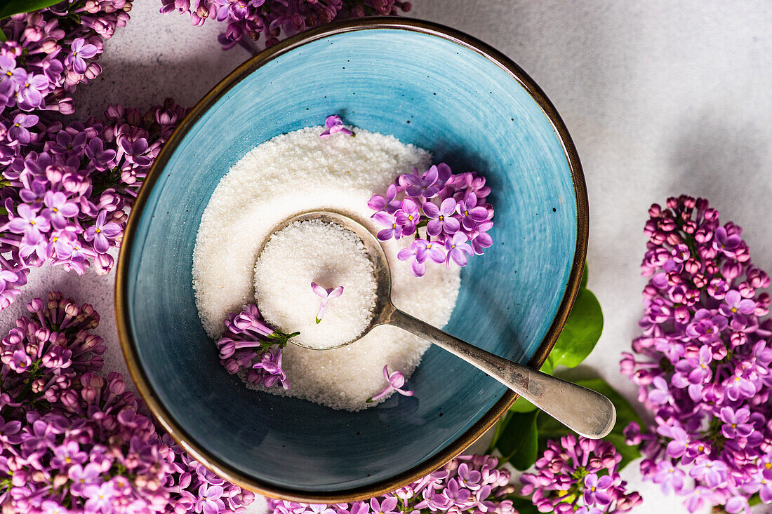 Bowl with sugard and lilac flower on rustic background