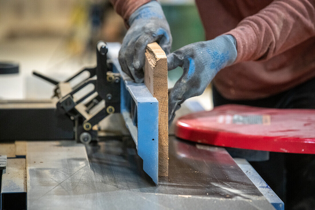 Man cutting pieces of lumber with table saw in wood shop
