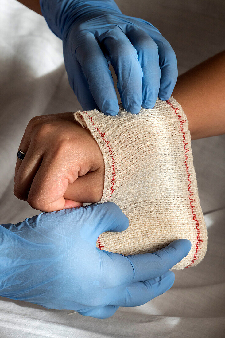 Nurse tying bandage on patient's hand