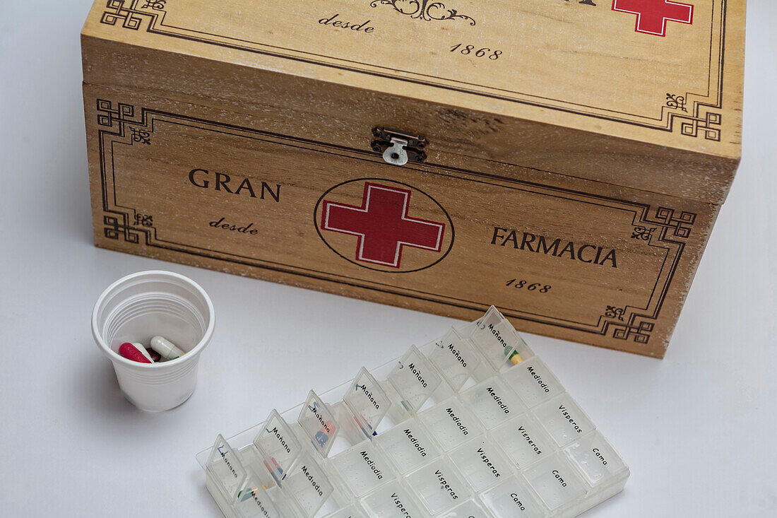 Pills with pill organizer next to old wooden kit