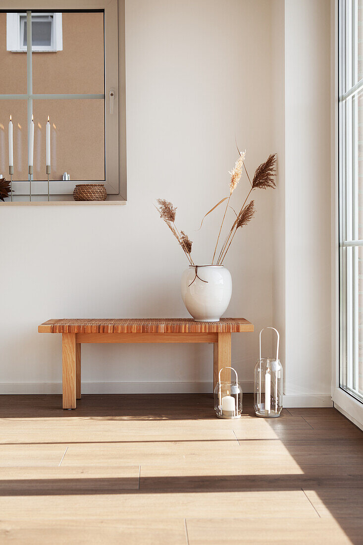 Vase filled with dried grasses on a bench, lanterns on the floor