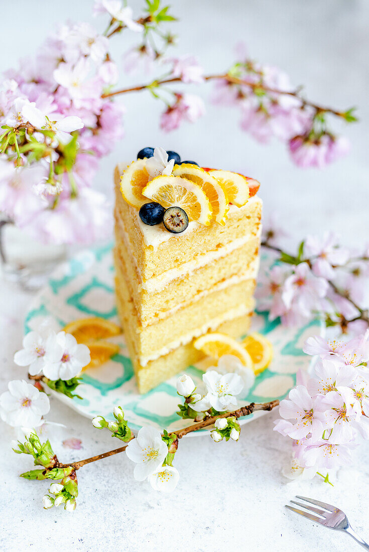 Ein Stück Zitronenkuchen, umgeben von Blütenzweigen