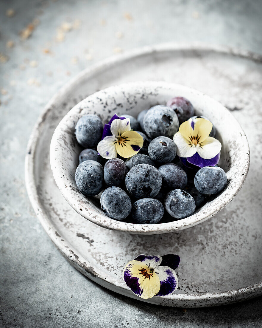 Heidelbeeren in einer Schüssel mit Stiefmütterchen