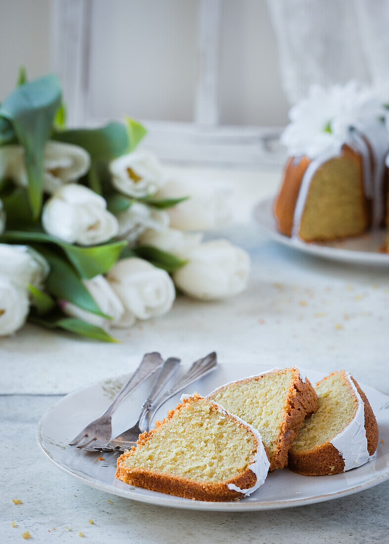 Bundt Cake in Scheiben auf Teller im Hintergrund Tulpen