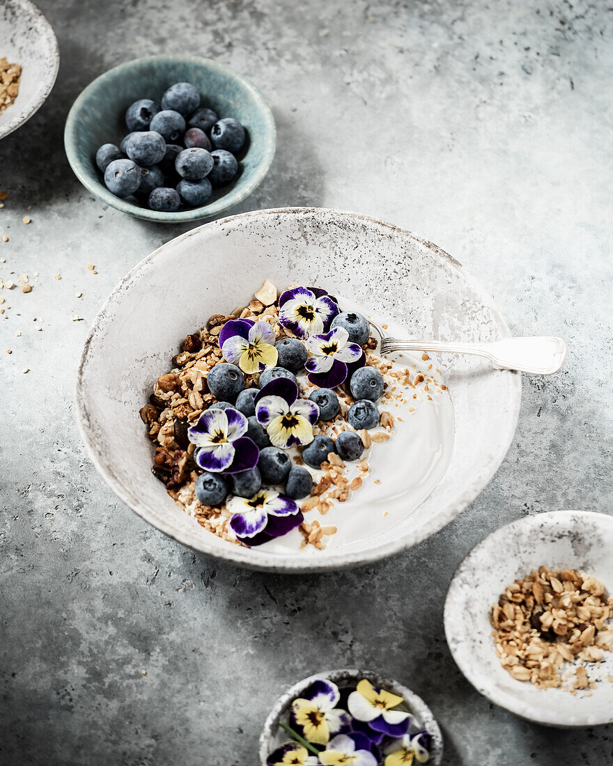 Yoghurt with muesli, blueberries and pansy blossoms