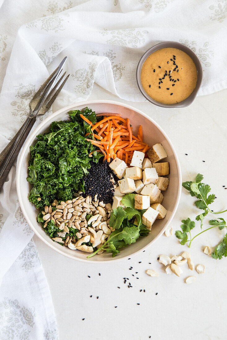 Healthy bowl with tofu, kale, carrots, sunflower seeds and sesame seeds