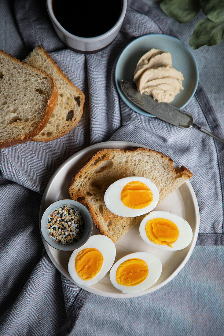 Frühstück mit getoastetem Brot, gekochtem Ei und Hummus