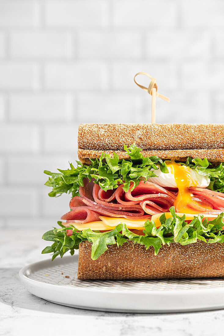 Sandwich mit Schinken, Käse, Salat und pochiertem Ei