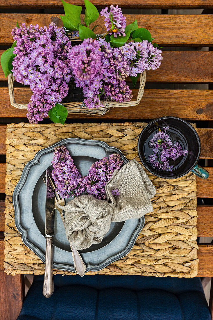 Spring table setting with purple lilacs on an outdoor table