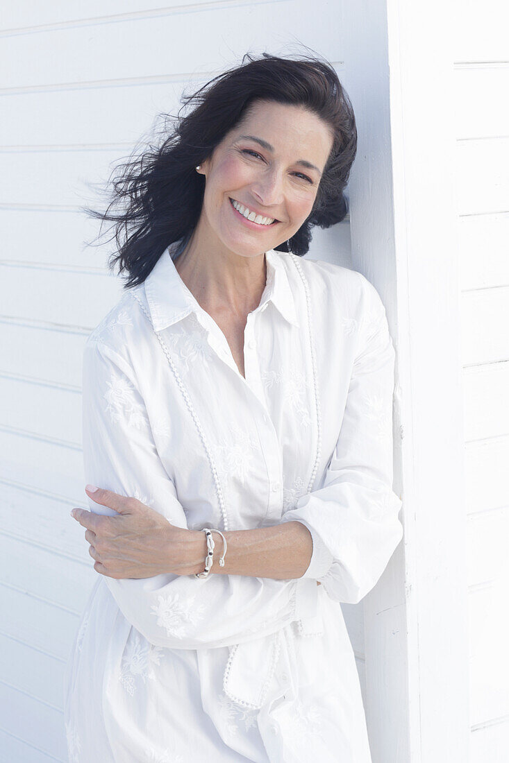 Mature dark-haired woman in white dress with embroidery