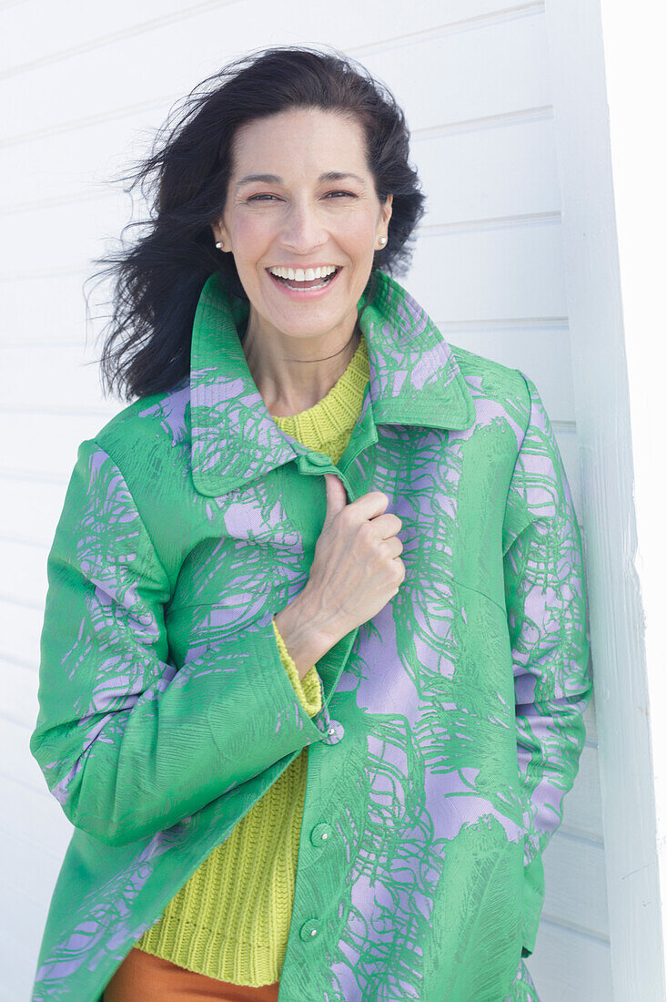 A mature, dark-haired woman wearing a green coat