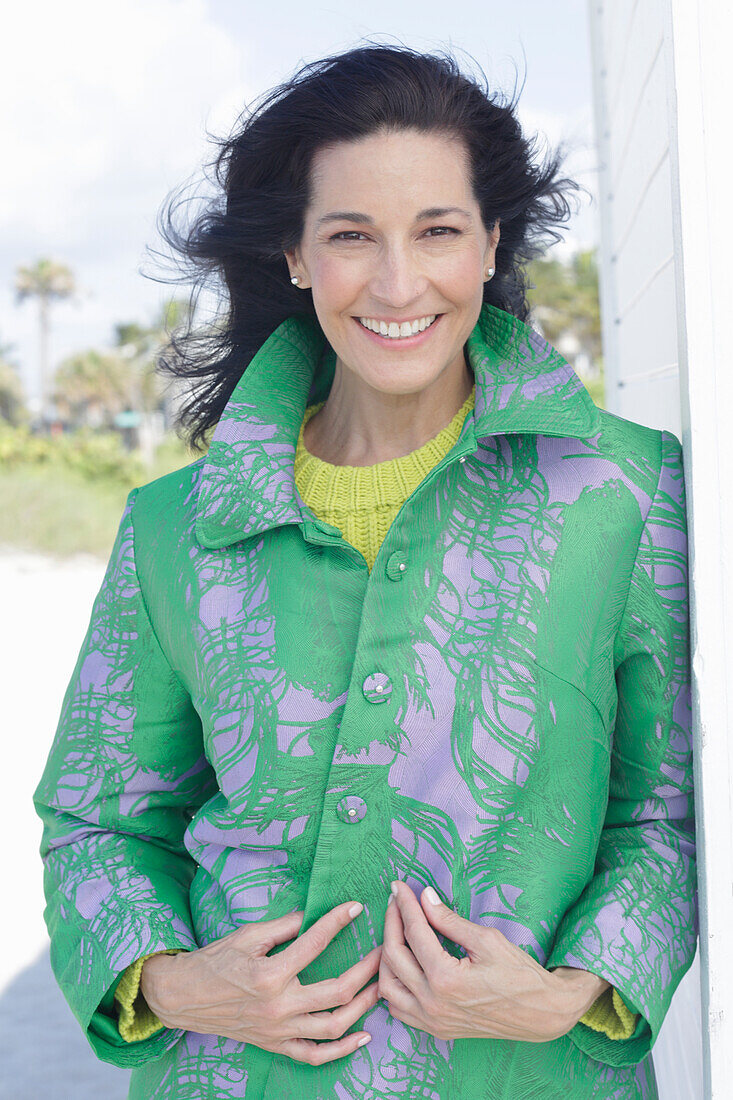 Mature, dark-haired woman in a green coat