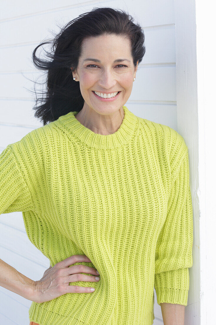 Mature, dark-haired woman in a green and yellow knit sweater