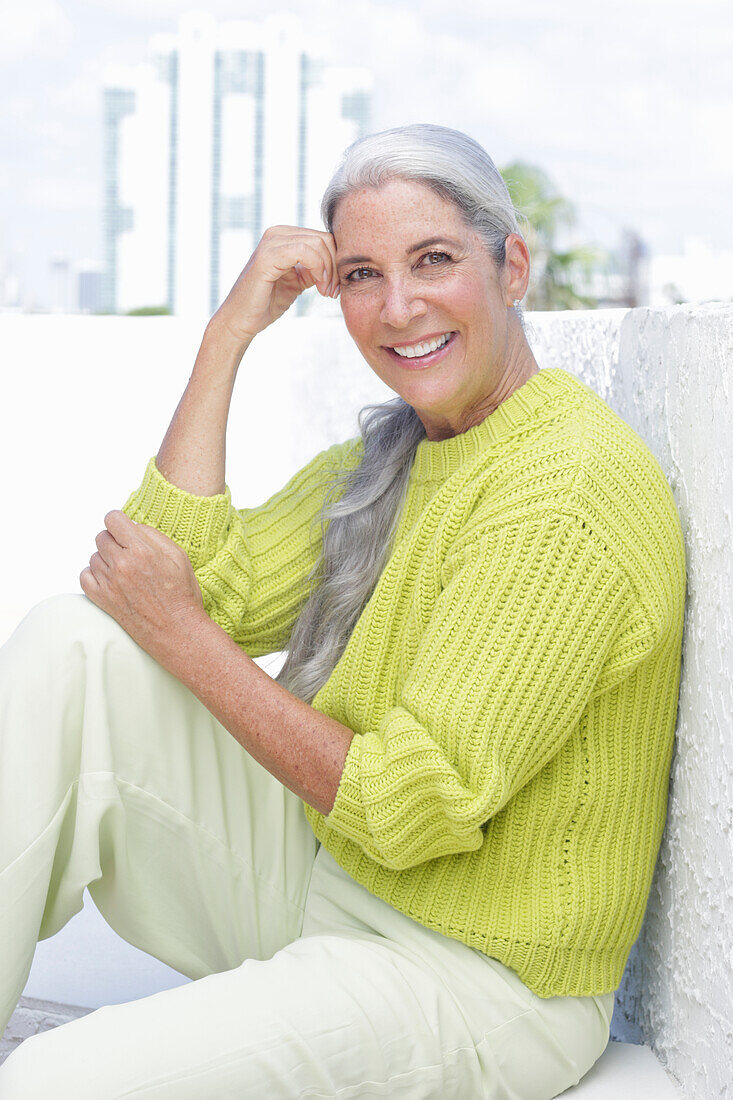 Gray-haired woman in a green-yellow knit sweater and light-colored trousers