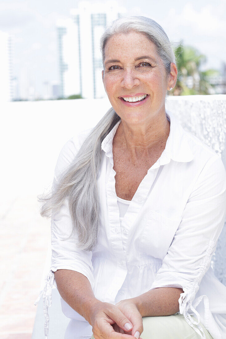 Woman with long gray hair in a white blouse