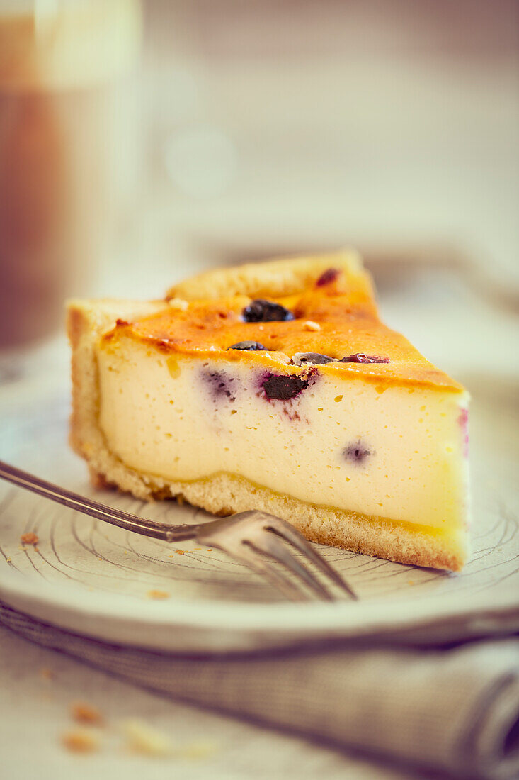 A slice of cheesecake with blueberries and shortcrust pastry