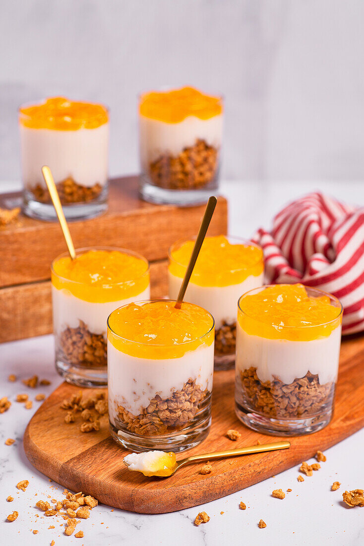 Joghurtdessert mit Müsli und Orangen-Mango-Mousse in Gläsern
