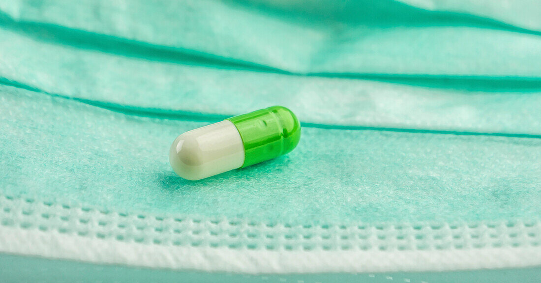Green and white pills on a facemask