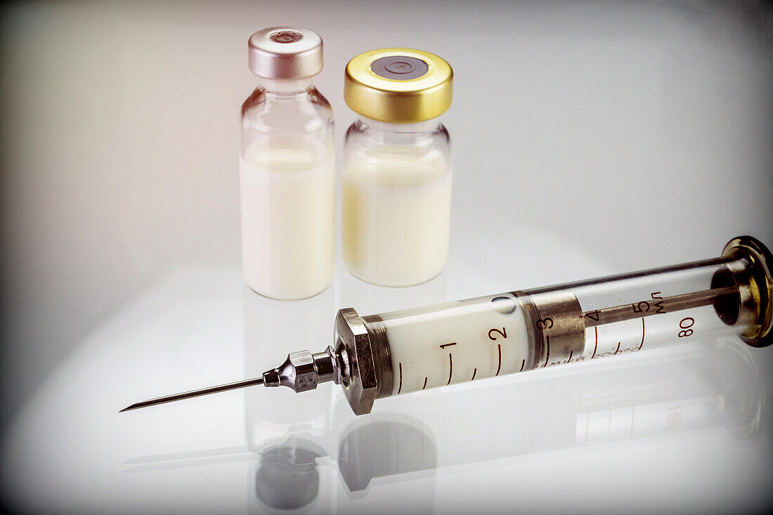 Syringe next to two vials with medicine