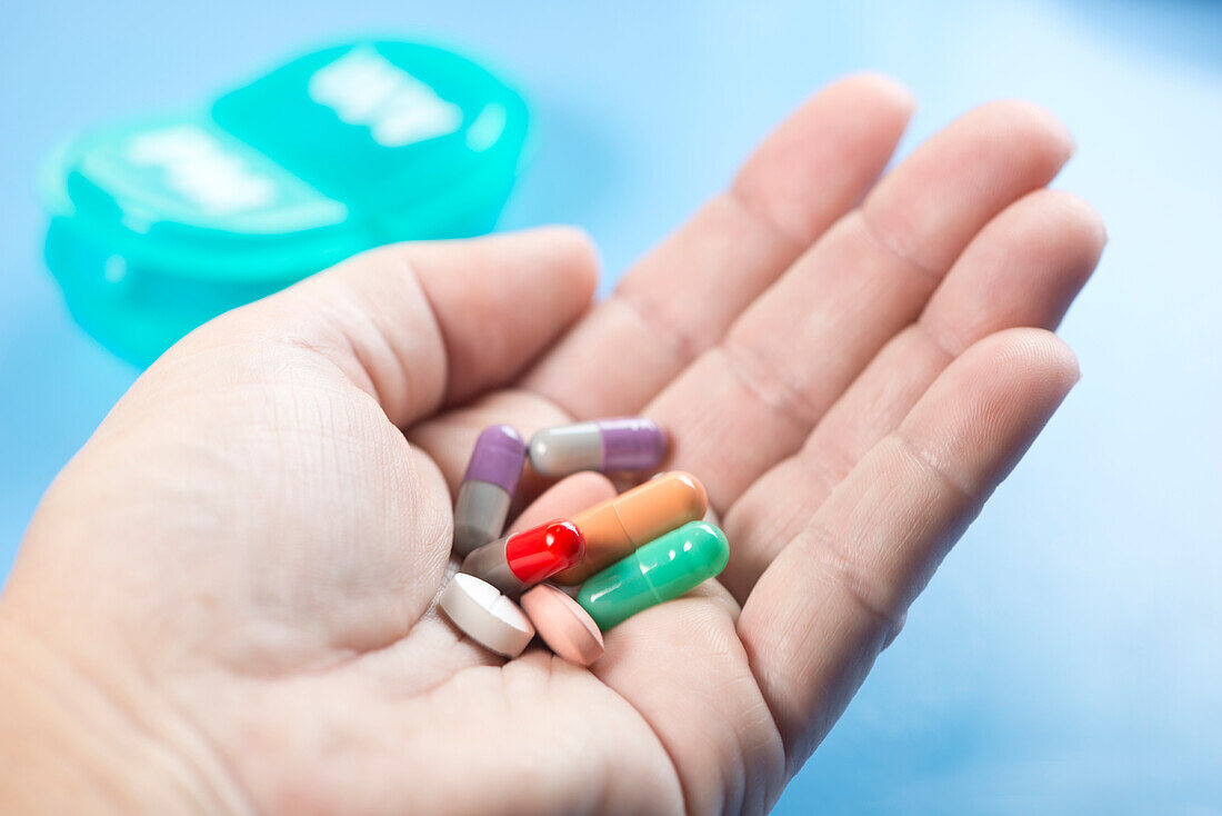 Daily medication in patient's hand with daily pill dispenser