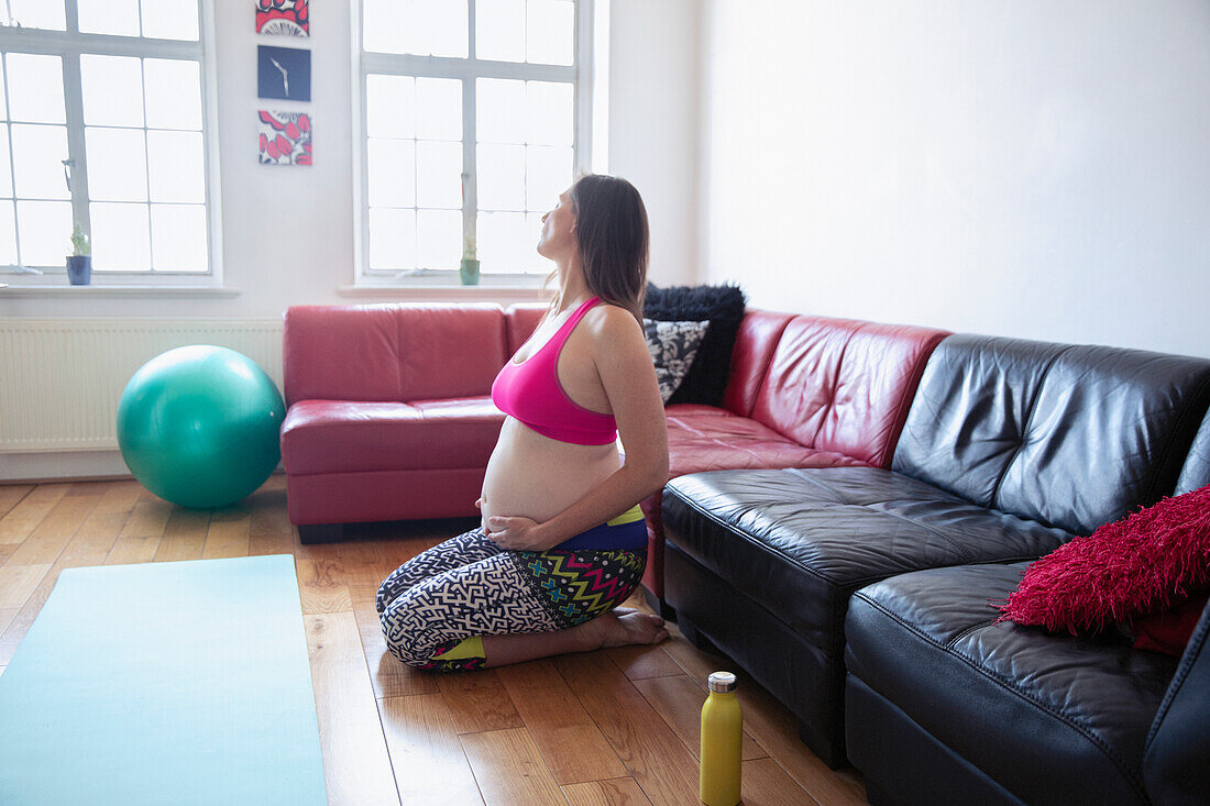 Pregnant woman exercising on living room floor