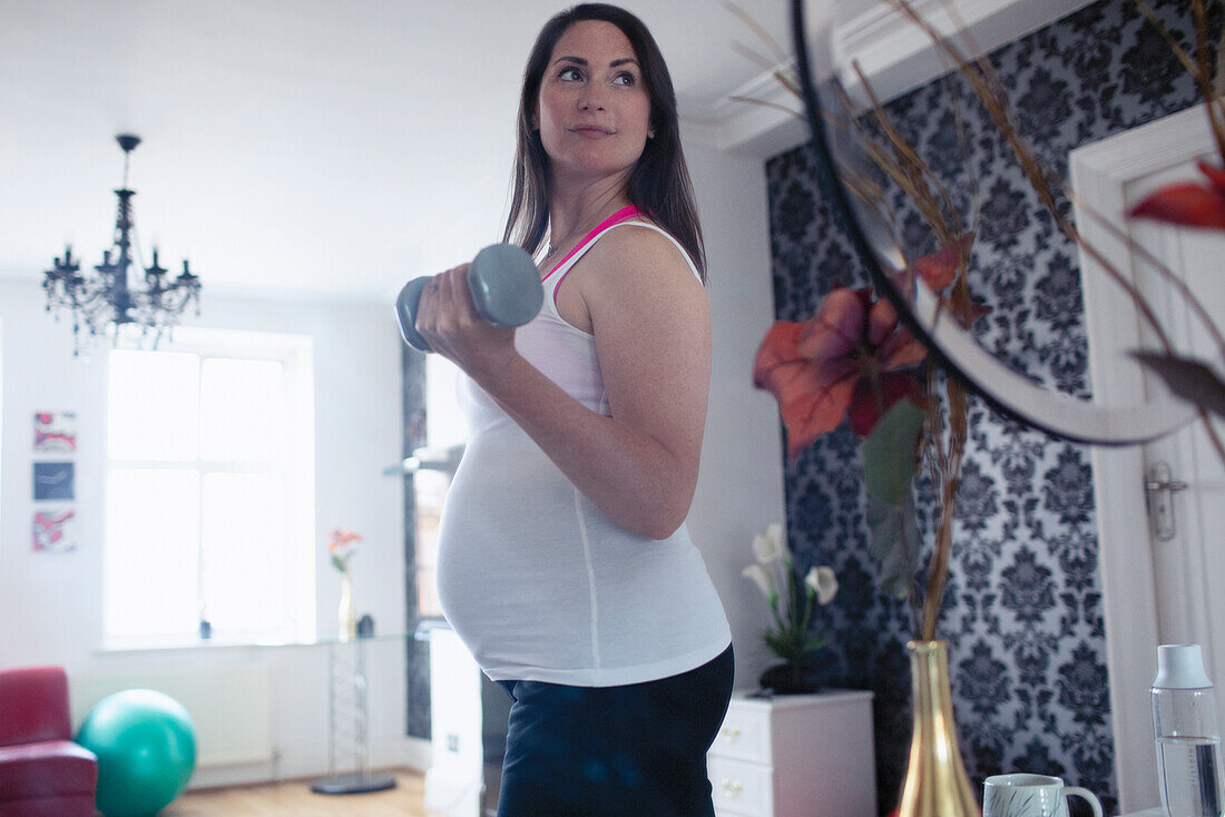 Pregnant woman with dumbbells working at home