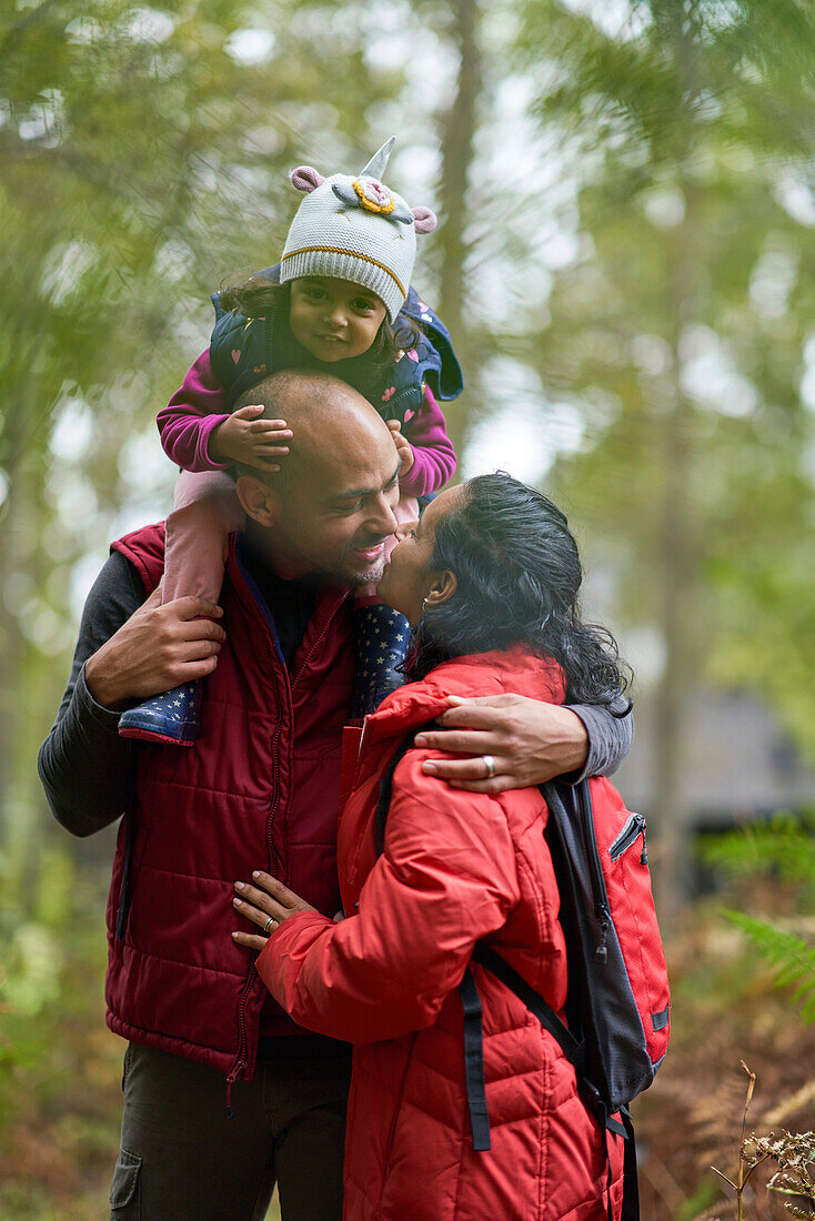 Affectionate couple with toddler daughter kissing on hike