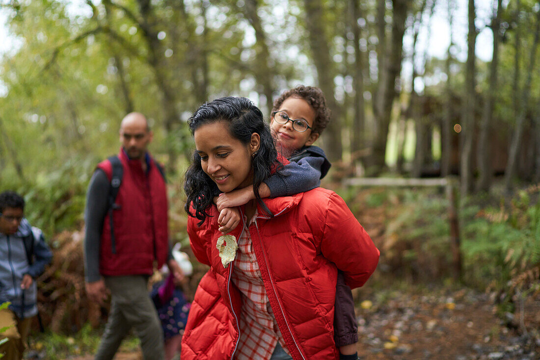 Mother piggybacking son on hike in woods