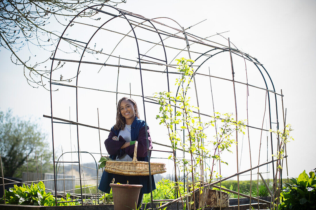 Smiling young woman under trellis in sunny garden