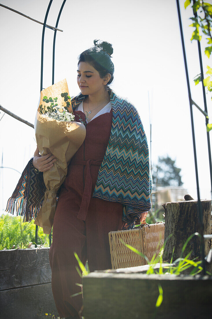 Young woman with a bouquet of flowers and picnic basket
