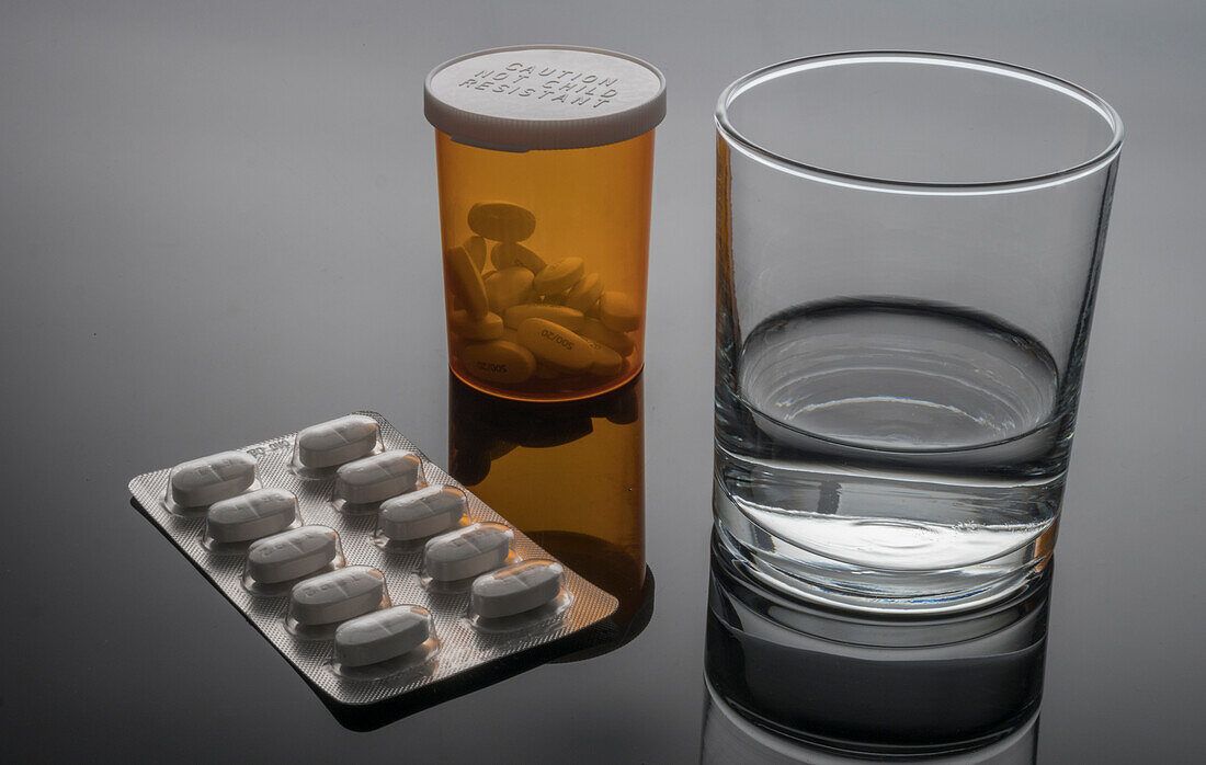 Glass of water next to blister pack of pills