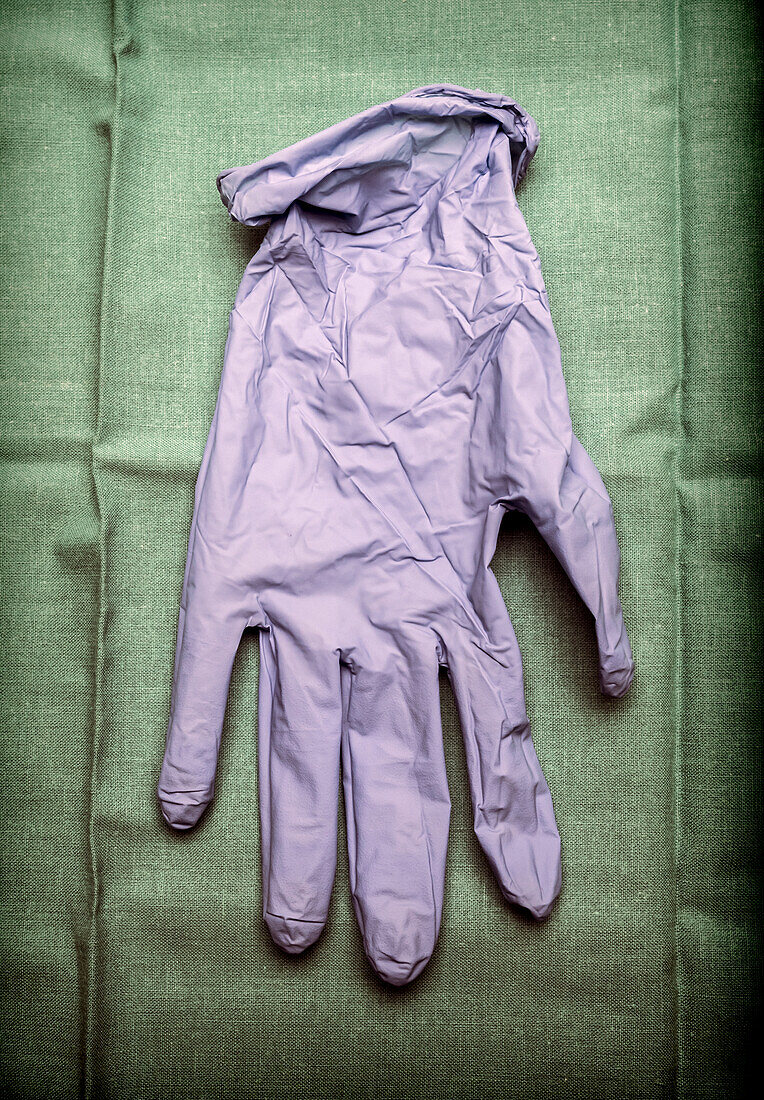 Glove of latex blue on green cloth in an operating theatre