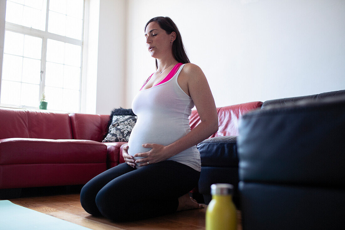 Pregnant woman doing breath work on living room floor