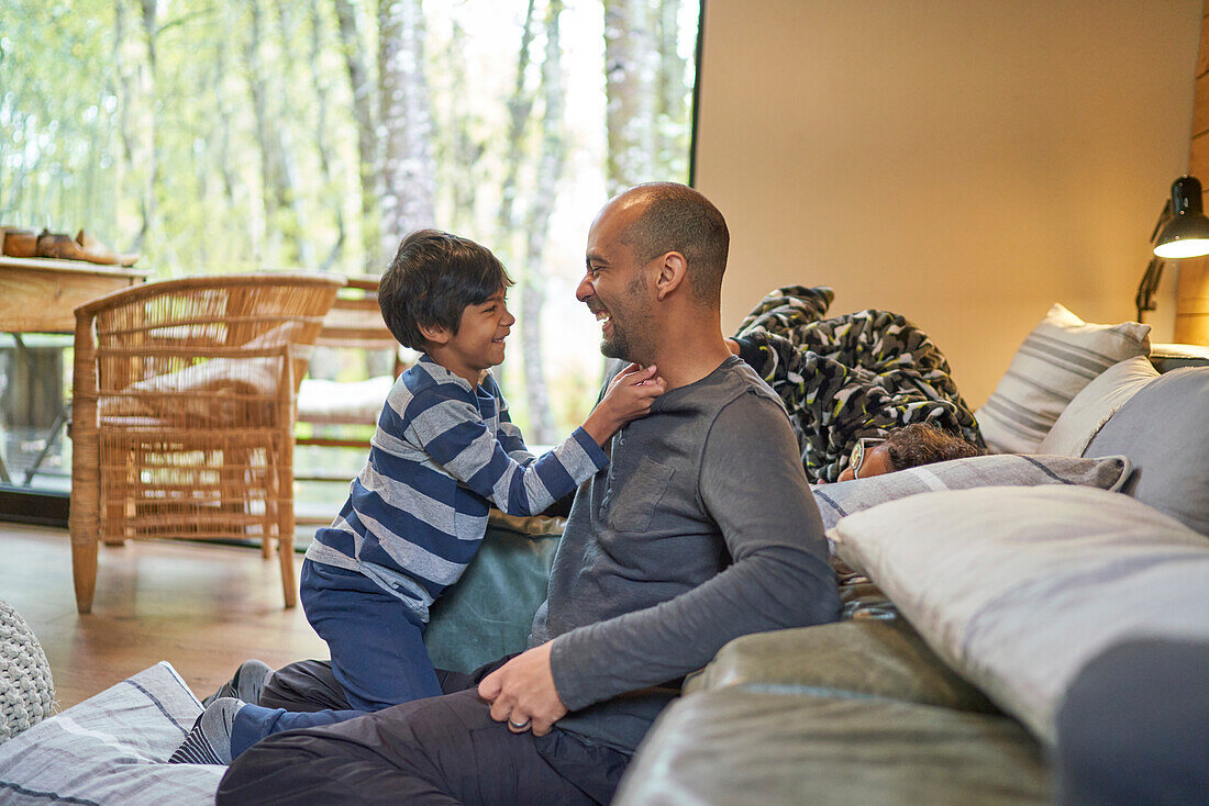 Happy father and son face to face in living room