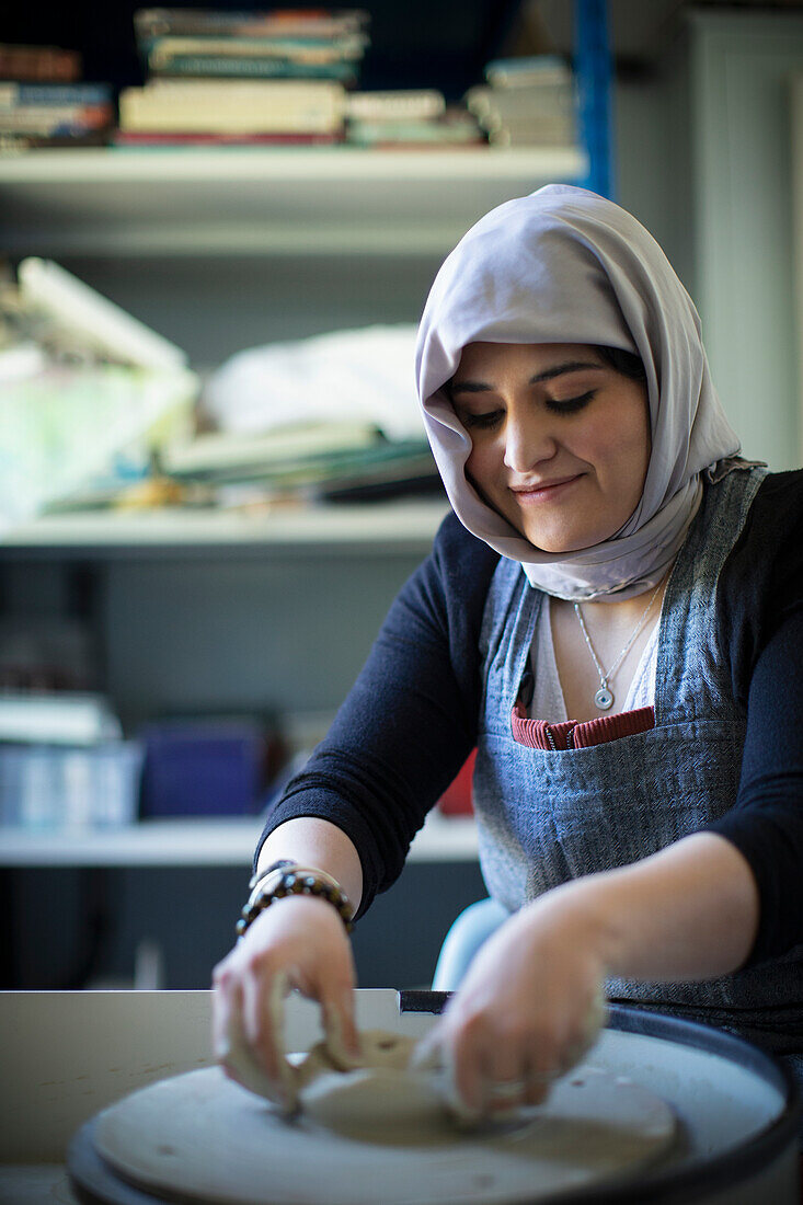Woman in hijab at pottery wheel
