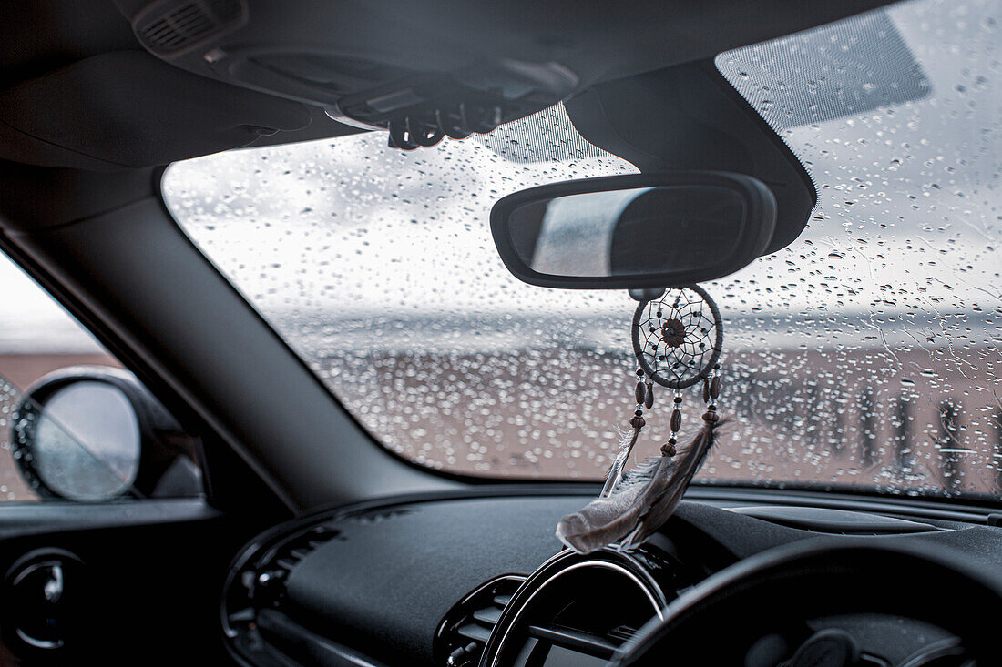 Dream catcher hanging from rear view mirror in car