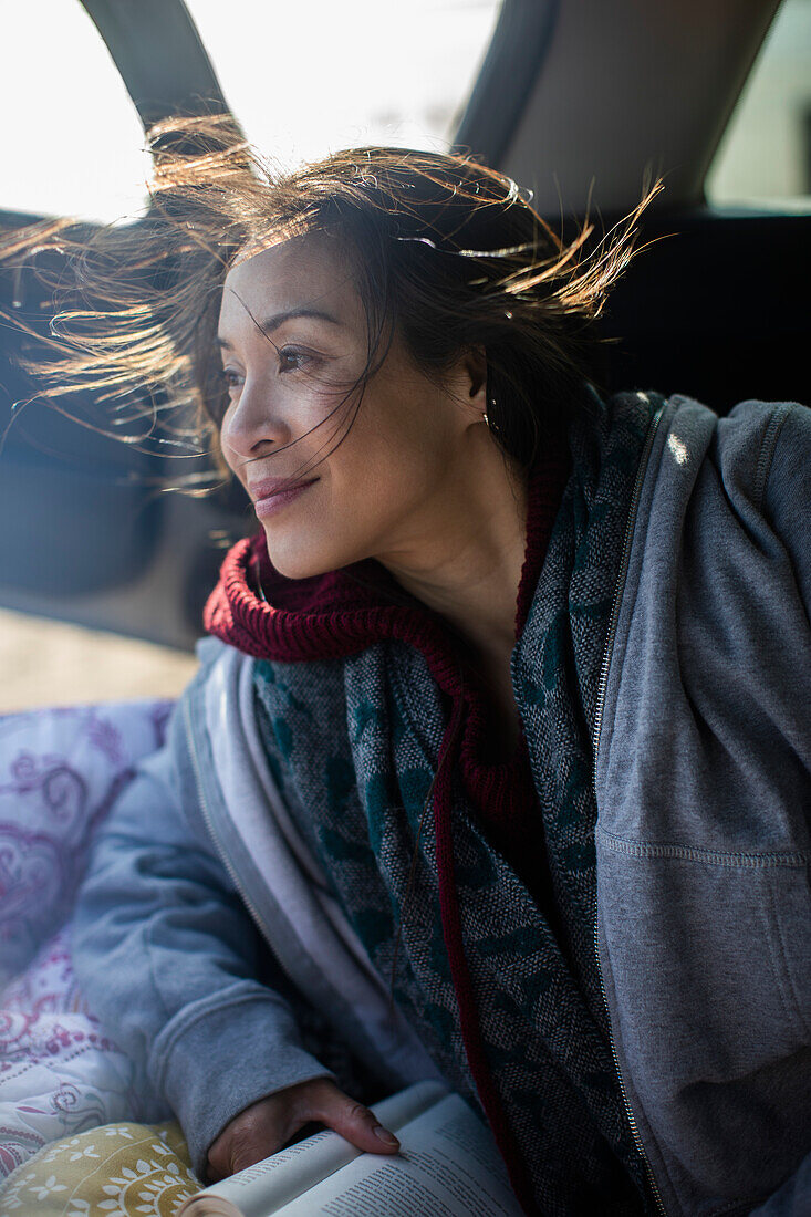 Carefree woman reading book in car