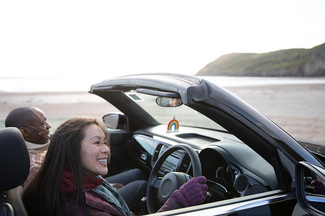 Happy couple driving convertible on winter beach