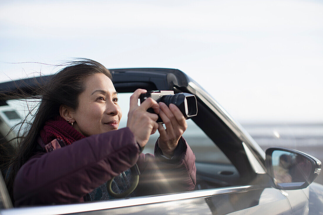 Woman with digital camera in convertible