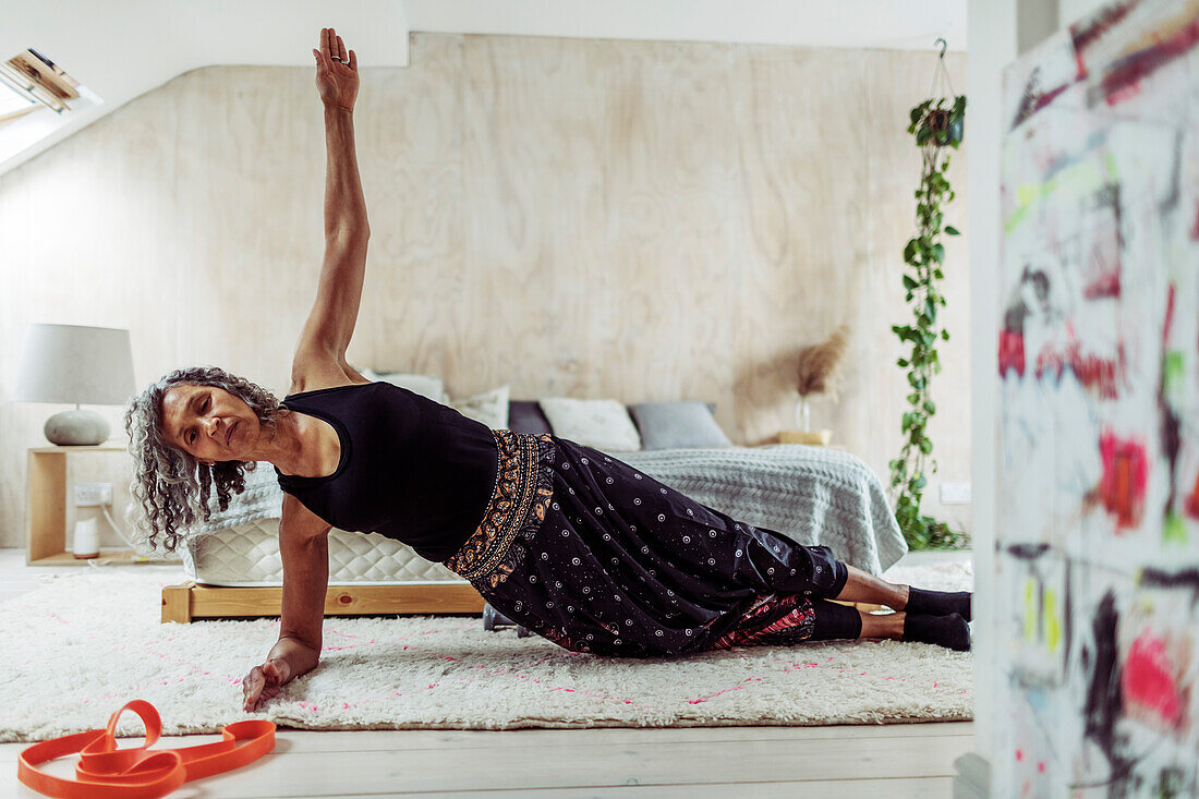 Woman exercising in side plank on bedroom rug