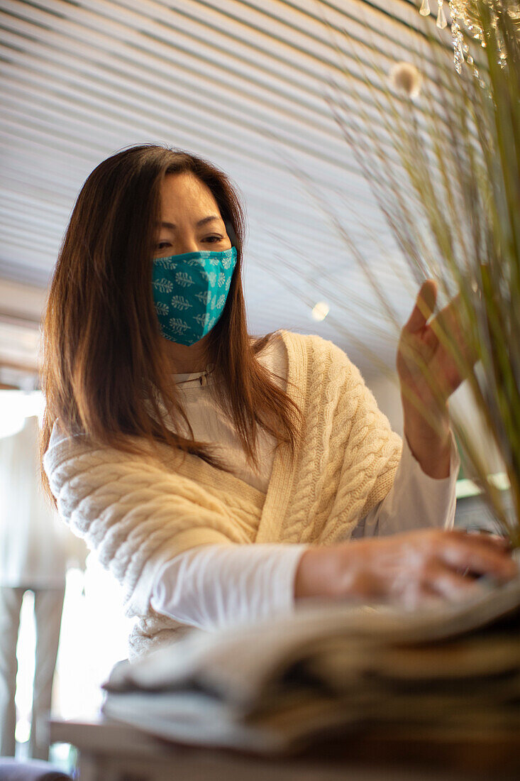 Female shop owner in face mask arranging display