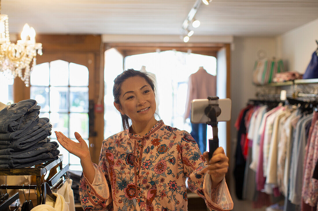Female shop owner vlogging with smart phone in boutique
