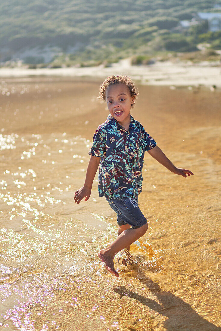 Carefree boy with Down Syndrome splashing in ocean