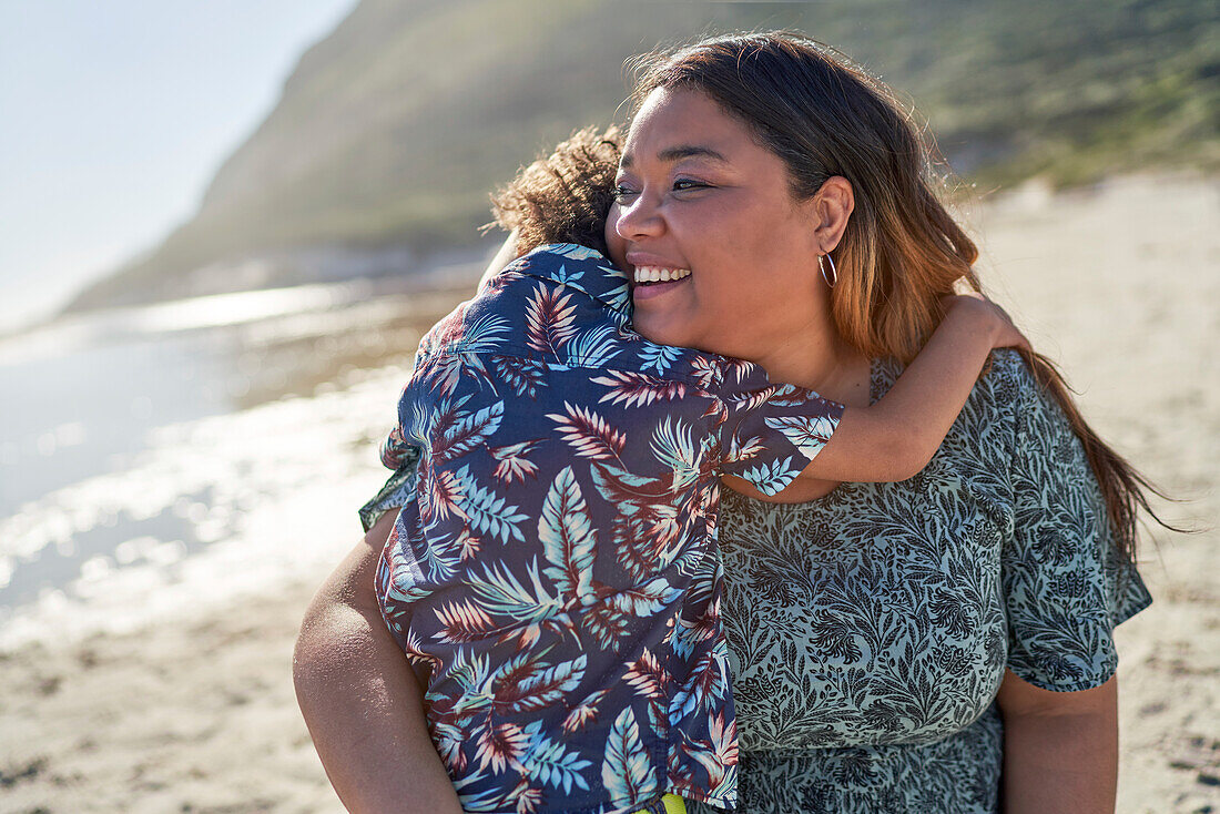 Happy mother hugging son on beach
