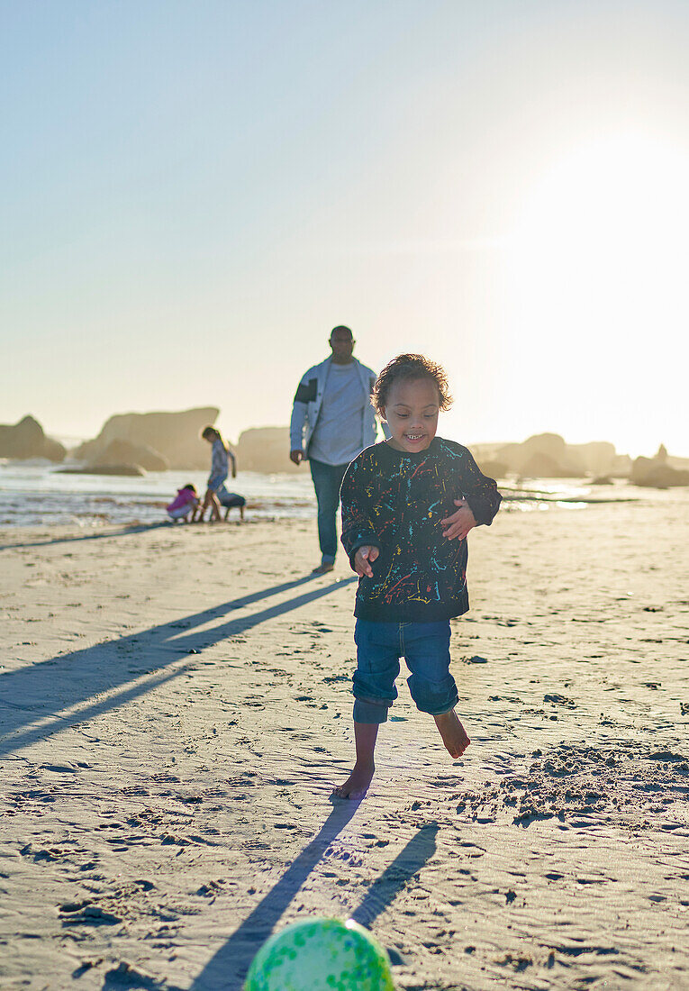 Carefree boy with Down Syndrome playing on beach