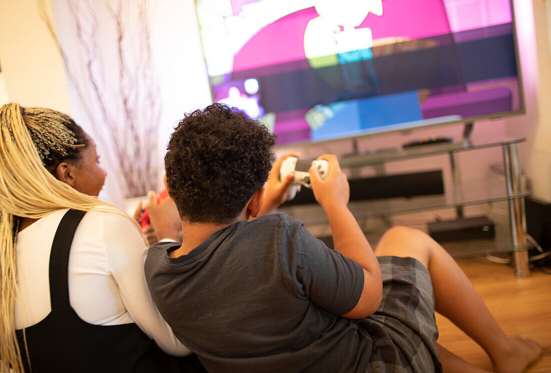 Mother and son playing video game in living room