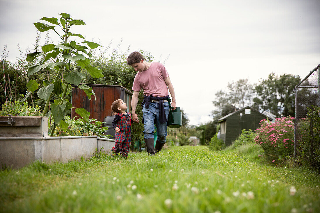 Father and toddler son walking in garden