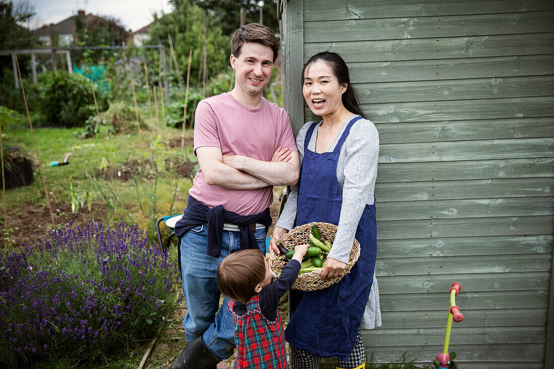 Happy family with harvested vegetables in garden