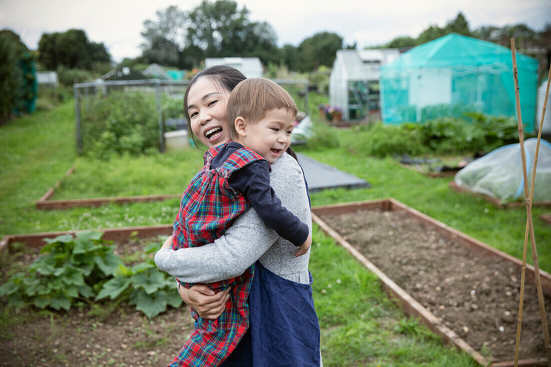 Happy mother and toddler son in vegetable garden